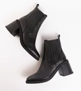 Botas tipo chelsea de cuero vacuno negro, con elásticos laterales, taco cuadrado y punta fina.
