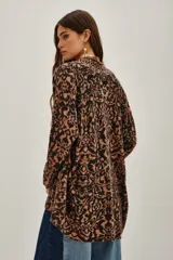 Saco de tejido de punto abierto, sin cuello ni cierre, con estampado tipo ikat o animal print en tonos marrón, negro y rosado pálido.