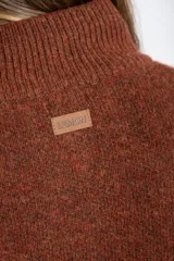 Cardigan de lana color marrón, con cuello alto, cierre frontal de botones y dos bolsillos delanteros. Presenta puños y ruedo acanalados.