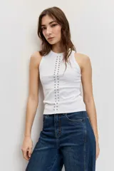 Musculosa blanca de ajuste ceñido con cuello redondo y detalle de apliques metálicos a lo largo de la parte frontal.