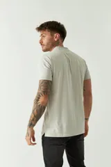 Remera polo de manga corta color tostado, con cuello clásico, cierre frontal de botones y un pequeño bolsillo en el pecho con logo estampado.