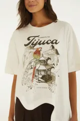 Remera blanca de algodón, de corte oversize y manga corta, con estampa frontal inspirada en la Floresta da Tijuca que incluye ilustraciones de un loro y un mirador.