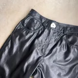 Pantalón de cuero vacuno negro, de tiro alto y corte recto con aberturas laterales en los bajos.
