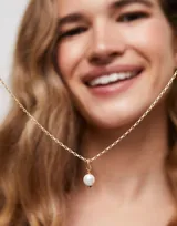 Dije charm bañado en oro de 18k con perla blanca colgante.