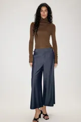 Pantalón culotte de tiro medio con pernera ancha y corta. Presenta nervios marcados en la parte delantera, bolsillos laterales y cierre frontal con cremallera, botón interior y hebilla ajustable en la cintura.