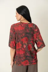 Remera estampada con motivos florales en tonos rojo y negro, de manga corta y corte holgado.