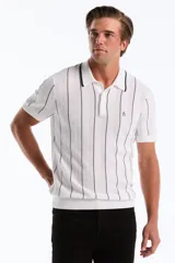 Chomba de punto blanca con finas rayas verticales negras, cuello polo con ribete oscuro, cierre frontal de tres botones y el logo del pingüino bordado en el pecho.
