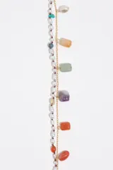 Pulsera de doble tira dorada combinada con cuentas de perlas y dijes colgantes de piedras naturales de colores, resina y perla barroca. Incorpora cierre de mosquetón con cadena de alargue.