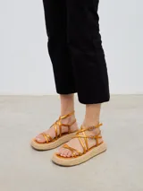 Sandalias con plataforma de esparto, tiras cruzadas color naranja y cierre con hebilla al tobillo.