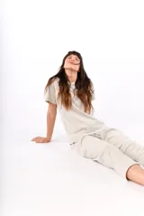 Conjunto de pijama de algodón color champagne, compuesto por una remera de manga corta con cuello henley y bolsillo en el pecho, y un pantalón capri a rayas horizontales celestes y blancas.