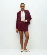 Short pollera de sastrería confeccionado en crepé, con diseño de frente traspasado, cintura alta estructurada y detalle de hebilla metálica lateral.