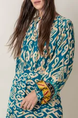 Vestido largo de viscosa con estampado abstracto en tonos azul petróleo y beige. Tiene mangas largas anchas terminadas en puño fruncido, corte en la cintura y bajo con volado y guarda.