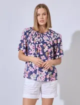 Blusa de gasa estampada con flores rosas y verdes sobre fondo azul marino. Escote bote con punto smock y mangas cortas amplias.