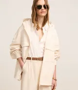 Campera oversized de poliéster color beige, con capucha ajustable, cierre frontal por cremallera y grandes bolsillos cargo en el frente. Presenta mangas largas con pliegues en los puños y diseño de estilo utilitario.