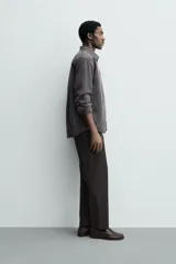 Pantalón de corte regular fit, color negro, confeccionado en tejido elástico. Presenta cintura elástica, cierre frontal con cremallera y botón, bolsillos laterales y bolsillos traseros de vivo.
