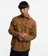 Camisa de manga larga confeccionada en sarga de algodón color verde menta, con cuello inglés y cierre frontal de botones negros. Presenta dos bolsillos de parche con solapa en el pecho y puños con botones.