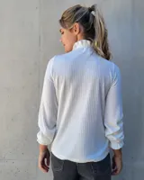 Polera de manga larga en tejido acanalado color blanco, con cuello alto y puños con detalle de punto smock fruncido.