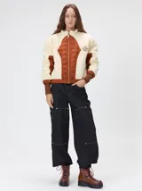 Campera crop de corte boxy y color negro, forrada en corderito, con parches capitoneados en el pecho y las mangas. Cuenta con cierre frontal metálico, cuello alto, puños y bajo elastizados, y detalle de logo bordado en hilo en el pecho.
