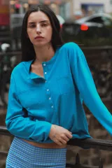 Camiseta rosada de manga larga con cuello panadero, cierre frontal con botones y bolsillos de parche en el pecho.