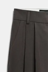 Pantalón de tiro medio con corte wide leg, presenta pliegues frontales, bolsillos laterales y trabilla con botón en la espalda. Cierre frontal con cremallera y botón.