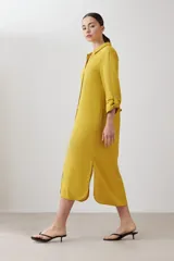 Vestido camisero midi color mostaza, de lino, con cuello camisero, mangas 3/4 con trabillas y cierre frontal con botones.