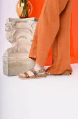 Sandalia de plataforma con base de corcho y suela gruesa. Tiras anchas ajustables con hebillas, combinando un estampado animal print marrón y plateado.