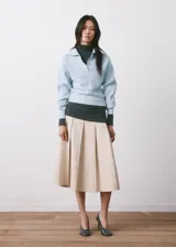 Sweater de punto celeste con cuello polo y cierre frontal en V, manga larga con puños ajustados y diseño acanalado.