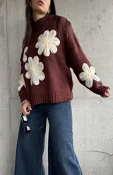Sweater de punto color chocolate con diseño de flores grandes en relieve en color crema y centro amarillo. Presenta cuello alto, mangas largas y corte holgado.