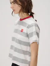 Remera de corte clásico a rayas horizontales en tonos verde y azul marino, con cuello redondo marrón y logo bordado en el pecho.