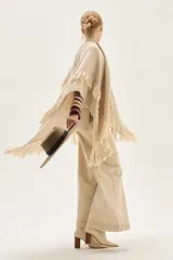 Ruana tejida en lana de cordero con diseño de sectores calados y terminación con flecos en los bordes.