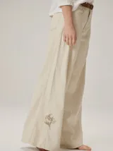 Pantalon de corte ancho y holgado, confeccionado en mezcla de algodón y lyocell. Presenta un diseño fluido con costuras verticales decorativas y bordado sutil en la pierna.