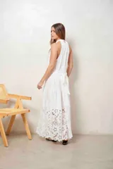 Vestido largo beige con cuello halter y detalle de broderie calado en el dobladillo inferior.