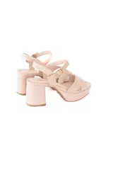 Sandalias de cuero color beige claro, con tiras cruzadas en la parte delantera, plataforma y taco ancho. Cuenta con tira ajustable al tobillo con hebilla metálica dorada.