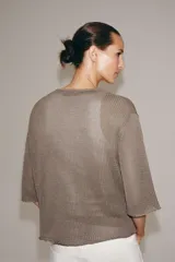 Chaqueta de punto color topo, con escote en V, mangas anchas por debajo del codo y cierre frontal de botones.