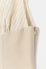 Top halter combinado con cuello subido ajustable mediante botones y hombros descubiertos, de diseño bicolor en tonos beige y blanco con sutiles rayas verticales.