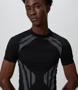 Remera masculina de poliéster seamless con corte ajustado, cuello redondo y manga corta. Presenta un diseño negro con perforaciones estratégicas y tramas geométricas en contraste en los hombros, laterales y frente.