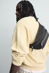 Riñonera negra de tejido técnico con múltiples compartimentos con cierre de cremallera, incluyendo uno frontal y uno interior. Posee asa ajustable con hebilla metálica de liberación rápida.