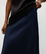 Pollera midi de satén color negro, con corte evasé y cintura elástica. Presenta una caída fluida y suave con acabado brillante.