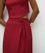 Pollera midi de estilo sastrero color bordó, con cintura estructurada, trabillas y lazo frontal en cordón del mismo tono. Presenta un corte recto y fluido.