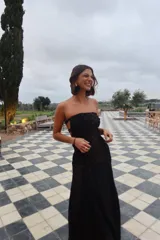 Vestido largo strapless de encaje negro con transparencias y espalda descubierta con tiras cruzadas, de corte entallado y falda de caída suelta.