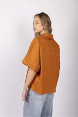 Camisa color ladrillo de corte holgado, con cuello camisero, mangas cortas con dobladillo y costuras a contratono.
