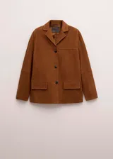 Blazer de cuero gamuzado color marrón, de corte recto y holgado, con solapas clásicas, cierre frontal de botones oscuros y bolsillos con solapa en el frente.
