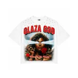Camiseta blanca de corte oversize con estampado gráfico frontal que presenta a una mujer con rayos saliendo de sus ojos, rosas rojas y el texto 'Glaza God' y 'Unleash The Power'. Incluye detalles de apliques metálicos en la parte superior.
