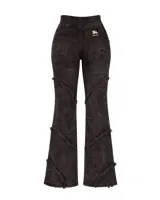 Pantalón de denim lavado color negro con diseño de recortes irregulares y terminaciones desflecadas. Presenta un corte entallado con botamangas ligeramente acampanadas.