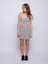 Conjunto de top y falda con estampado floral en blanco y negro. El top es de breteles finos y la falda es corta con volados.