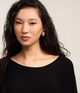 Suéter de tricot color negro con escote canoa, mangas murciélago y puños ajustados.