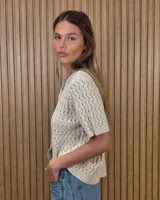Cardigan calado de manga corta, tejido en punto con cierre frontal de botones y cuello redondo.