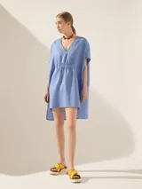 Túnica blanca de lino con corte asimétrico, mangas cortas y escote en V con pespuntes.