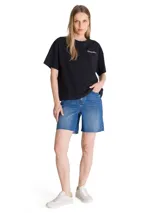 Remera de algodón color negro, con cuello redondo y mangas cortas. Presenta un diseño minimalista con el logo de la marca bordado en el pecho y un parche bordado en la manga izquierda.