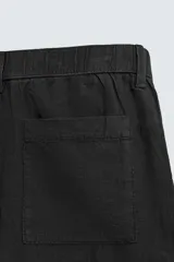 Bermuda de corte relajado confeccionada en lino, con cintura elástica, pliegues frontales, bolsillos laterales y cierre frontal con cremallera y botón.